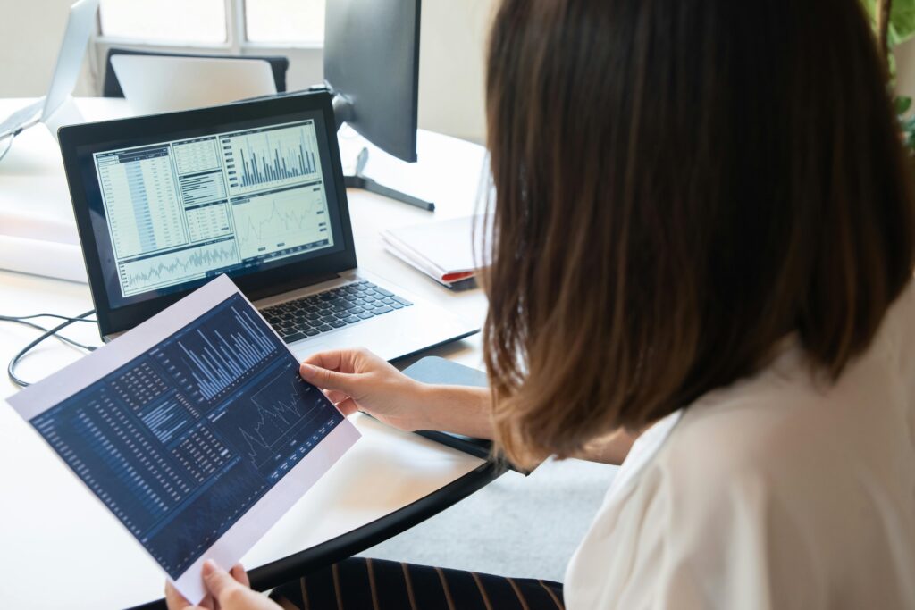Owner reviewing printed Google Ads performance reports beside a laptop with charts