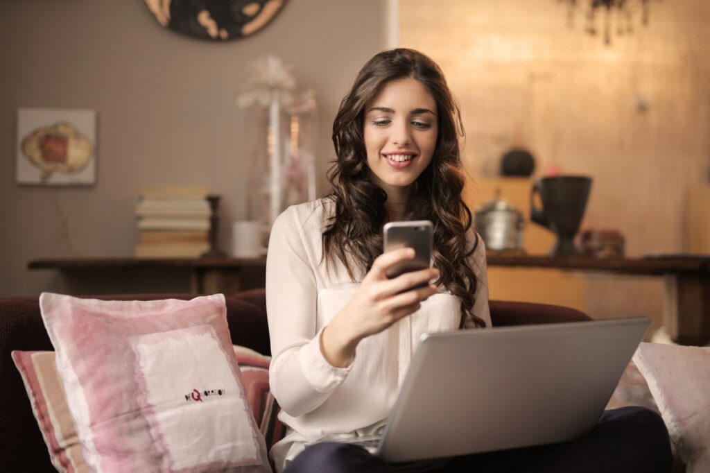 Homeowner scrolling her phone on the couch, where Facebook ads for electricians get seen