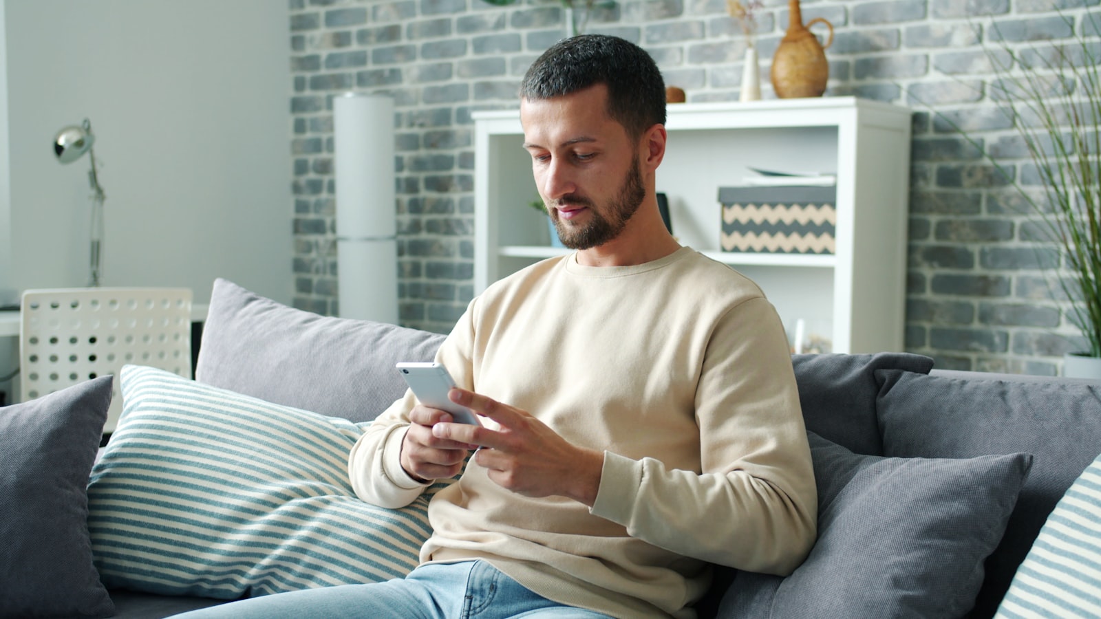 Homeowner scrolling a phone on the sofa, where a retargeting ad reaches someone who already visited your site