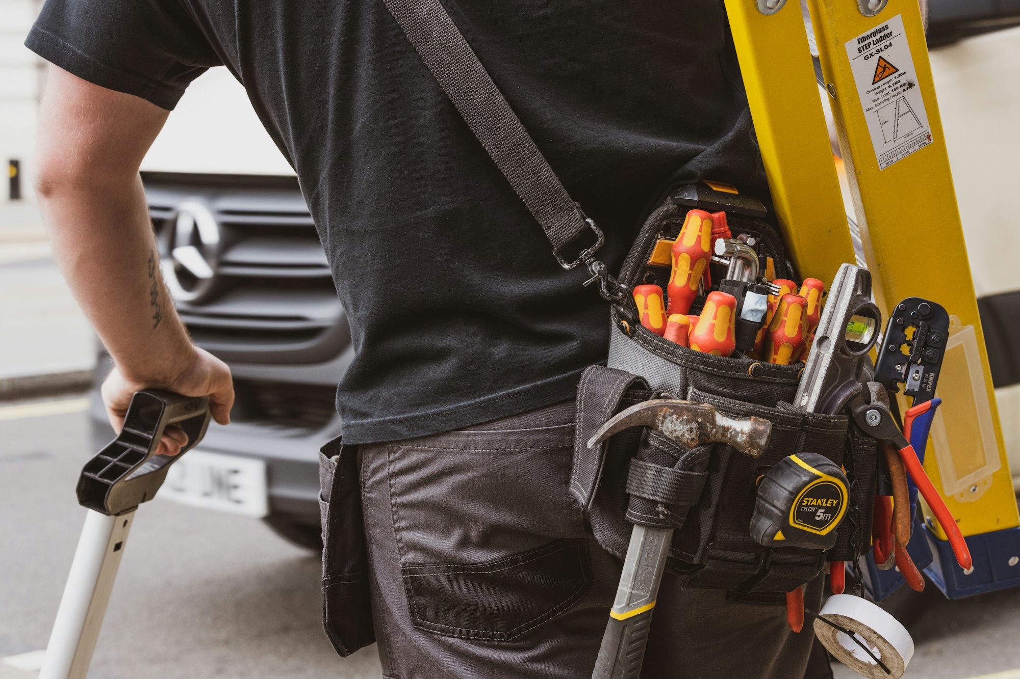 HVAC technician with a tool belt heading into a spring maintenance appointment