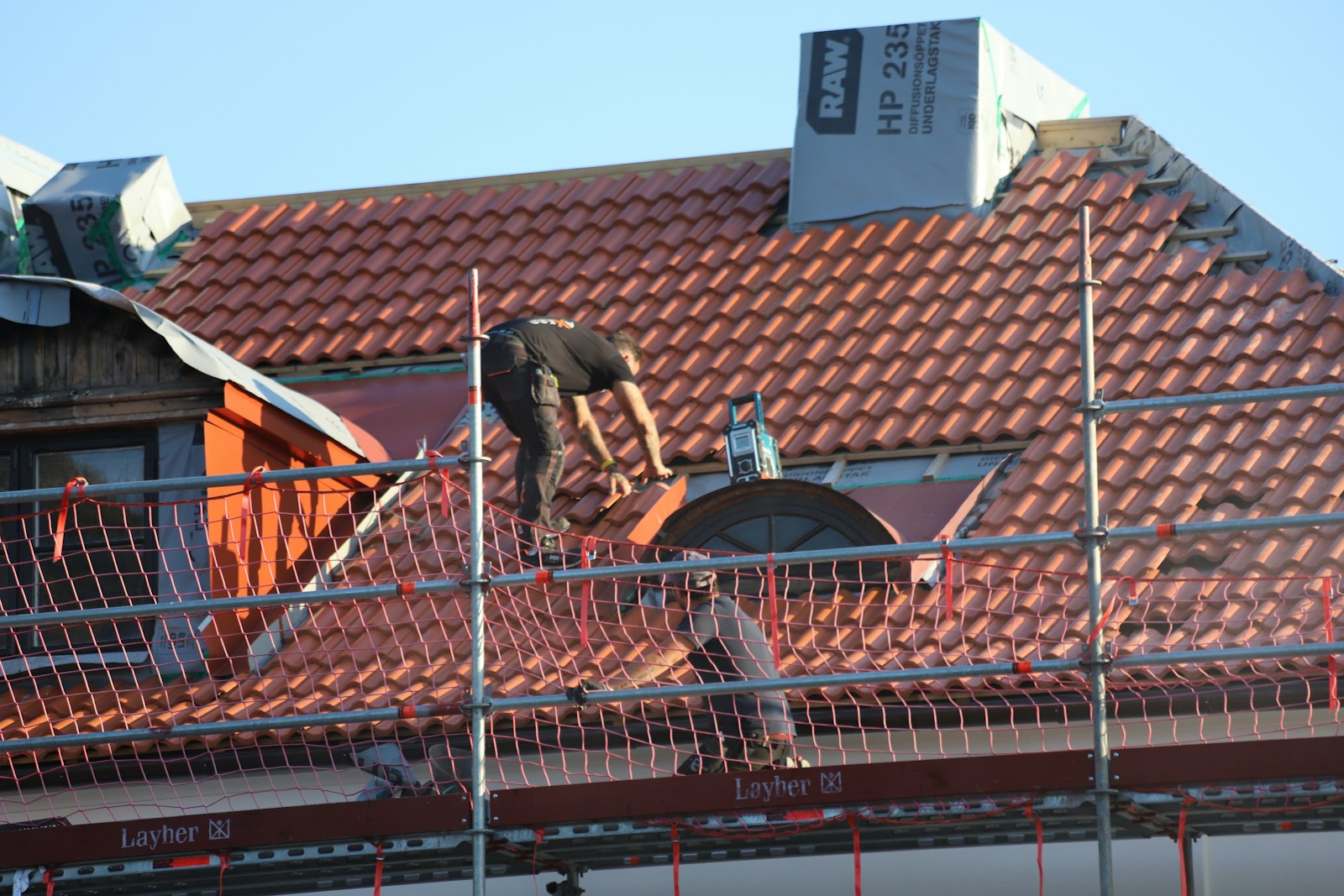 Roofer on a residential roof replacing shingles torn loose in a storm