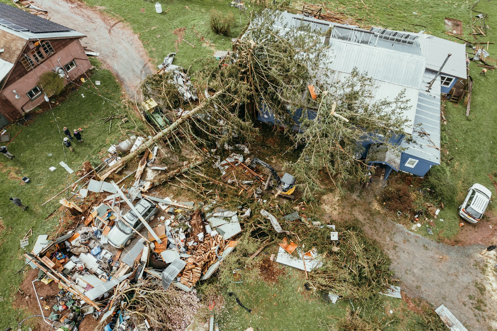 Aerial view of a home with a storm damaged roof and debris across the yard